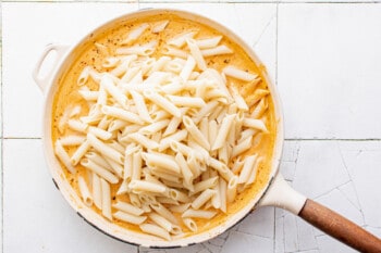 penne pasta being mixed into the vodka sauce