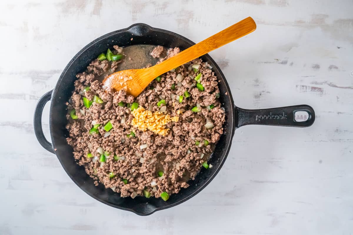 stirring grouns beef with other ingredients in a skillet.