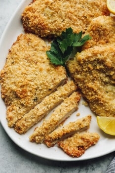 parmesan crusted chicken, one is partially cut into thin slices