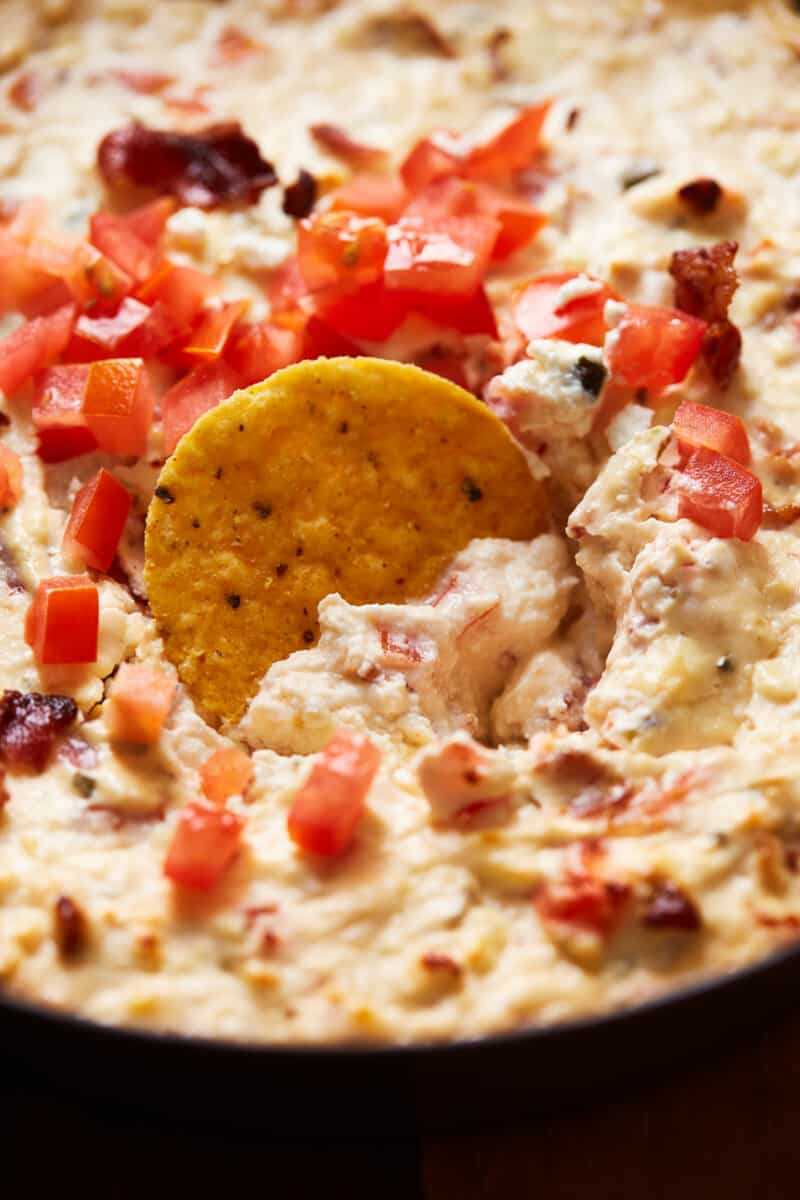 a tortilla chip dipped into hot bacon feta dip