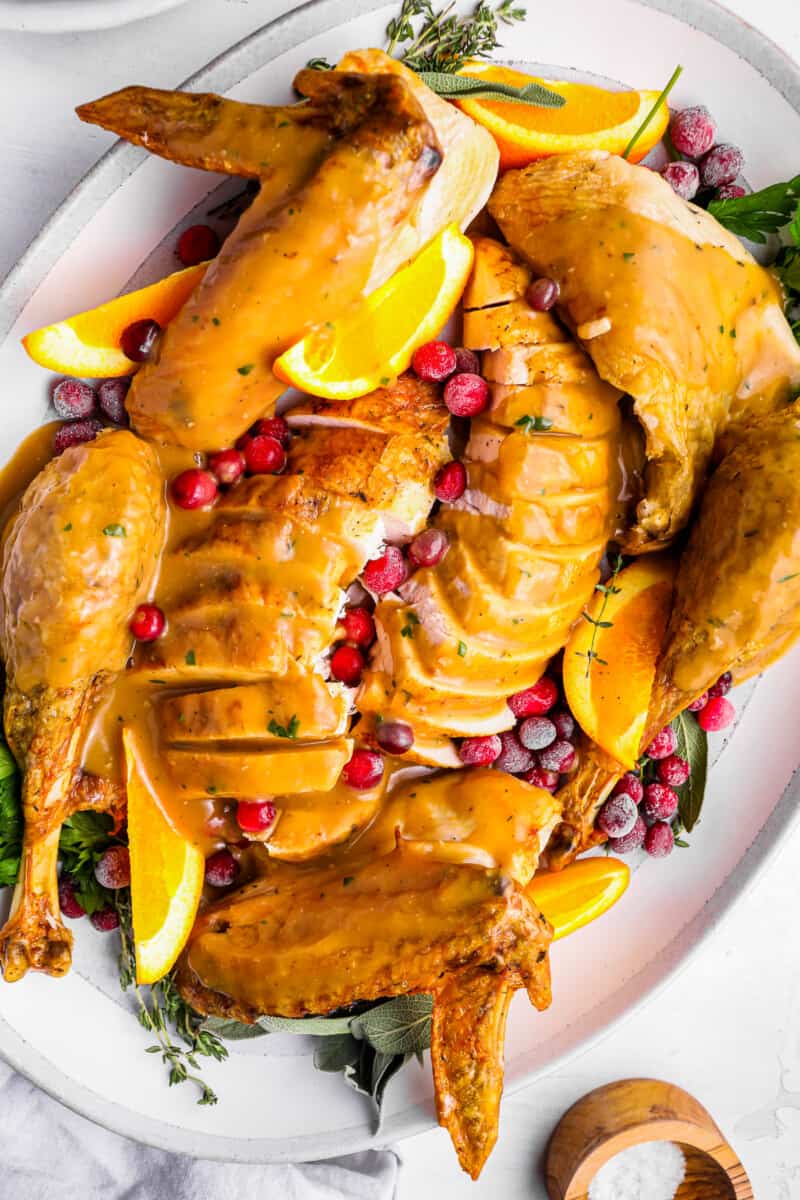 turkey gravy on top of a sliced whole turkey on a white plate.