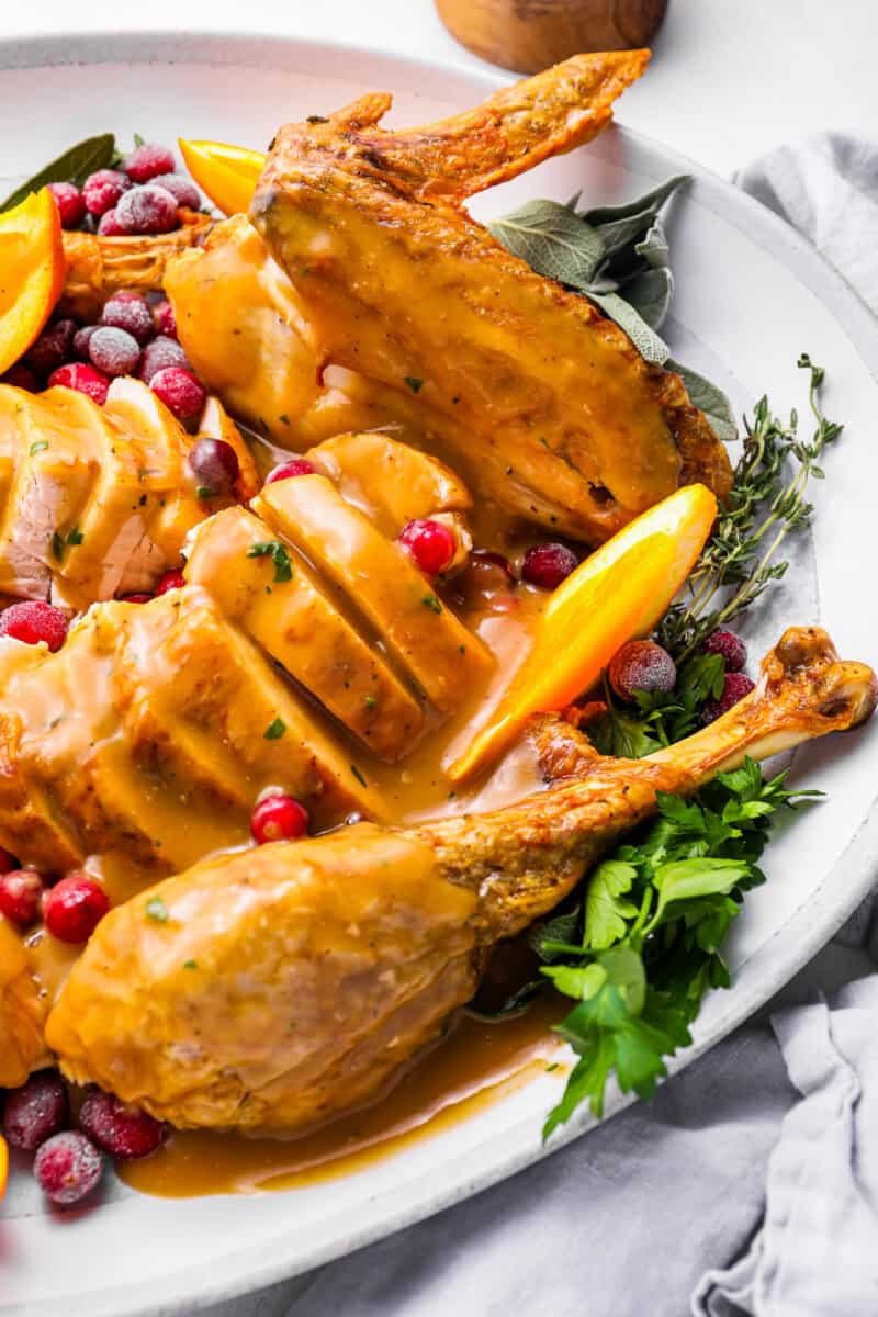 turkey gravy on top of a sliced whole turkey on a white plate.