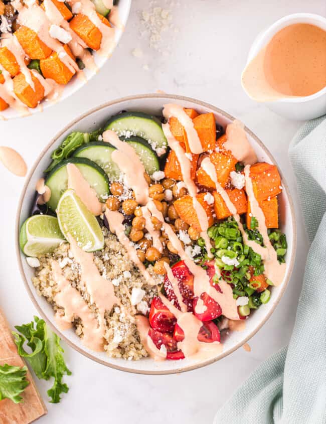 overhead view of a buddha bowl drizzled with sriracha mayo dressing in a white bowl.