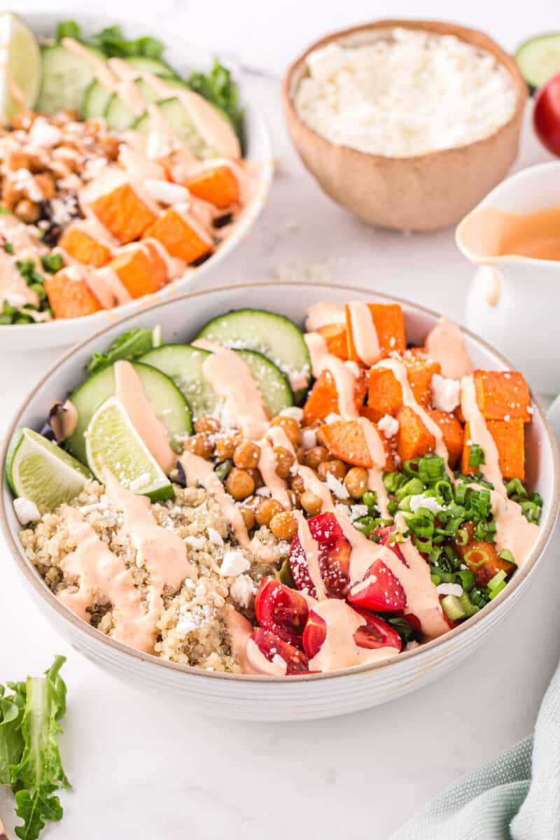 2 buddha bowls drizzled with sriracha mayo dressing in white bowls.