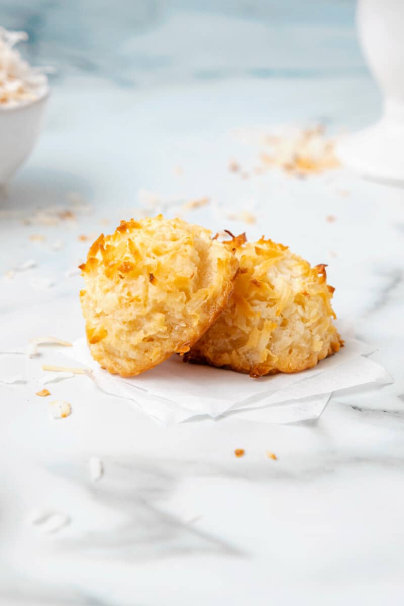 close up of a coconut macaroon leaning against another coconut macaroon.