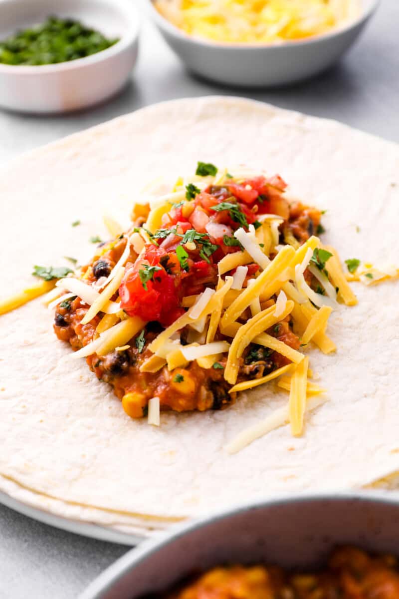 crockpot chicken burrito filling in the center of a flour tortilla on a white plate.