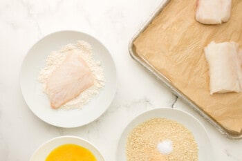 a piece of fish dipped in flour on a white plate.