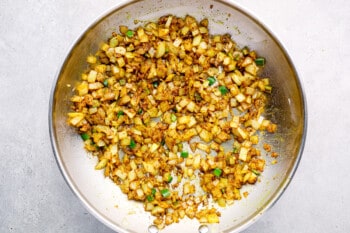 crispy onions and spices in a stainless frying pan.