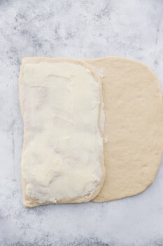 cronut dough folded in thirds and buttered on a marble counter.