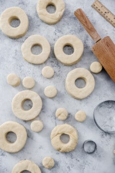 cut out cronuts and cronut holes on a marble table.