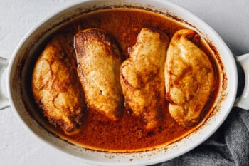 baked marinated chicken breasts in a white oval baking dish.