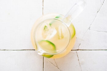 a pitcher of lemonade sitting on a tiled floor.