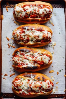 overhead view of meatball subs on a lined baking sheet.