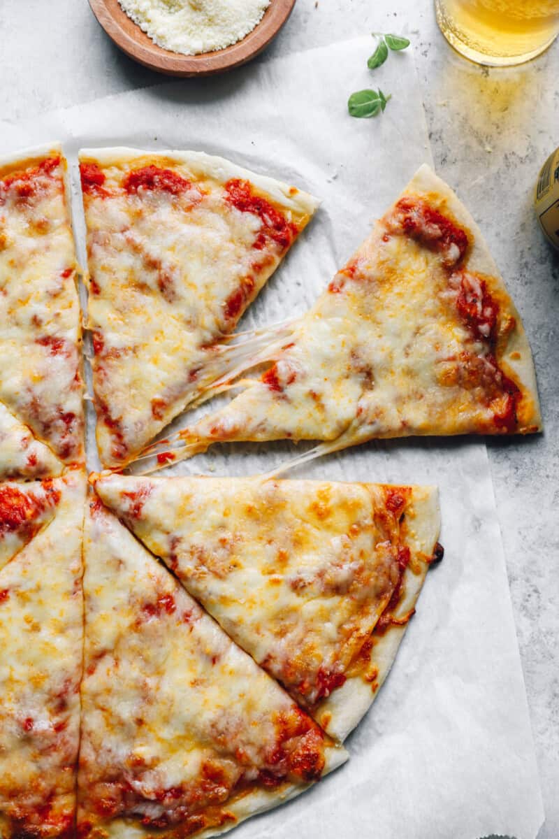 overhead view of a sliced new york style pizza on parchment paper.