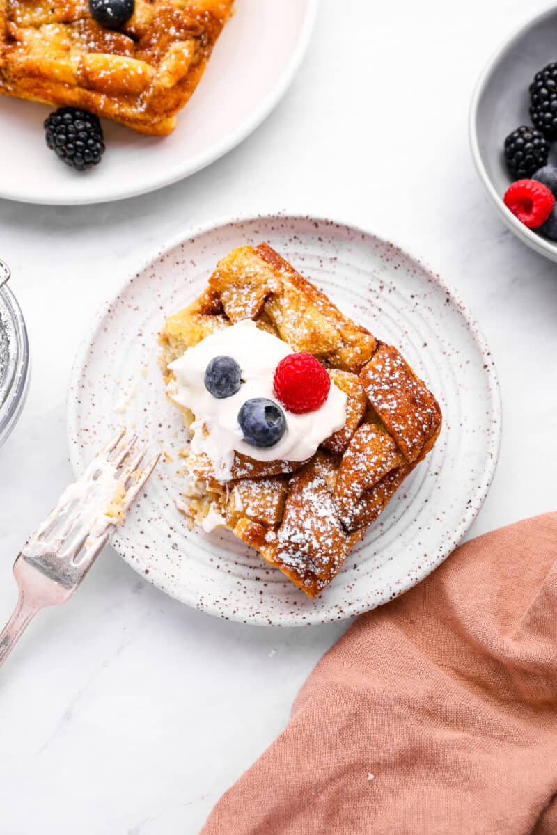 a partially eaten serving of bread pudding on a white plate with a fork.