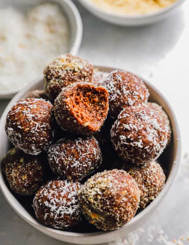 a bitten rum ball on top of a bowl of rum balls.