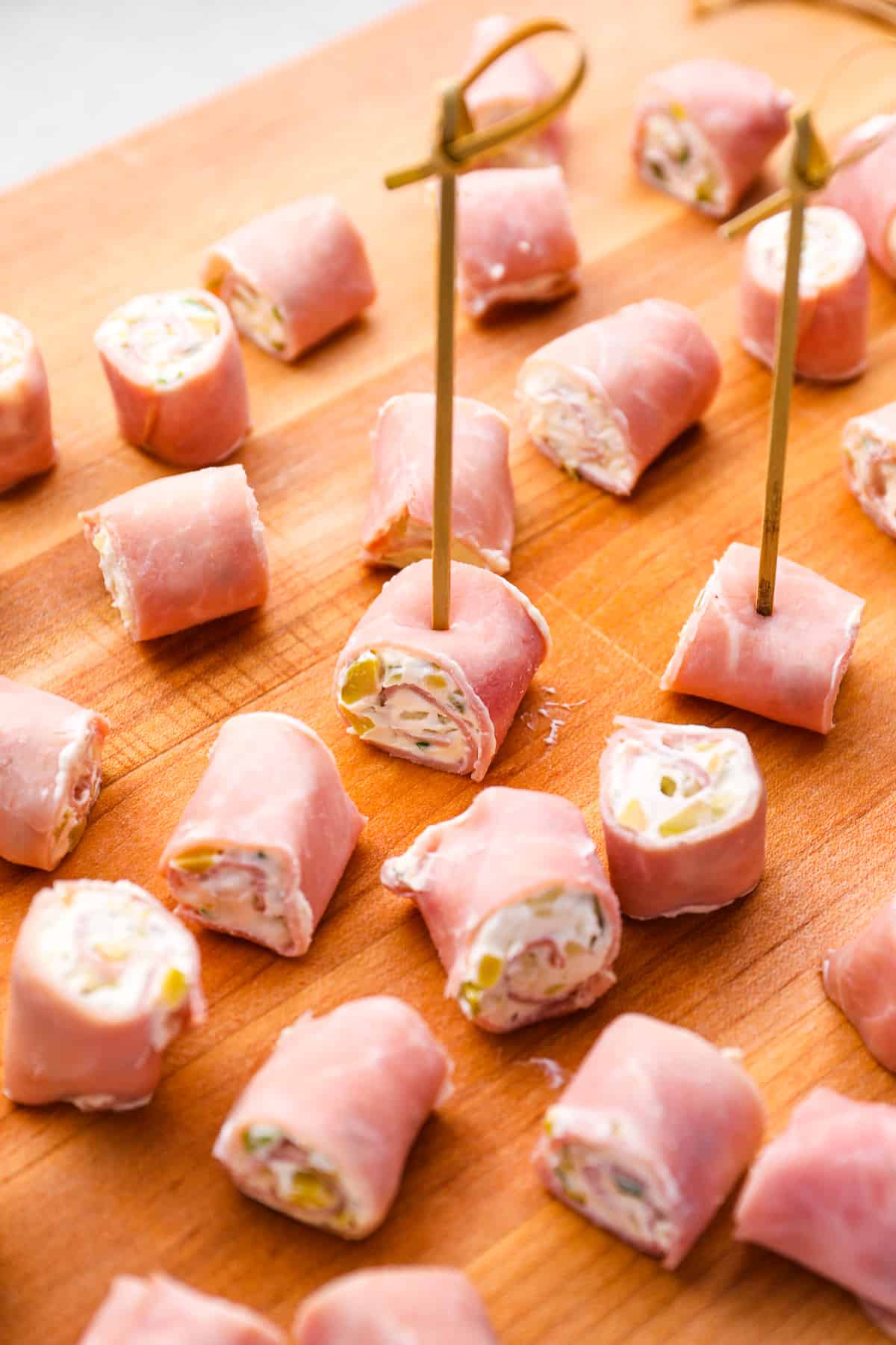 skewered ham roll ups on a wooden cutting board.