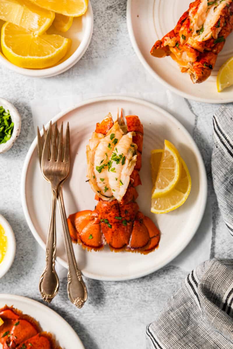 a lobster tail on a white plate with a fork and knife.