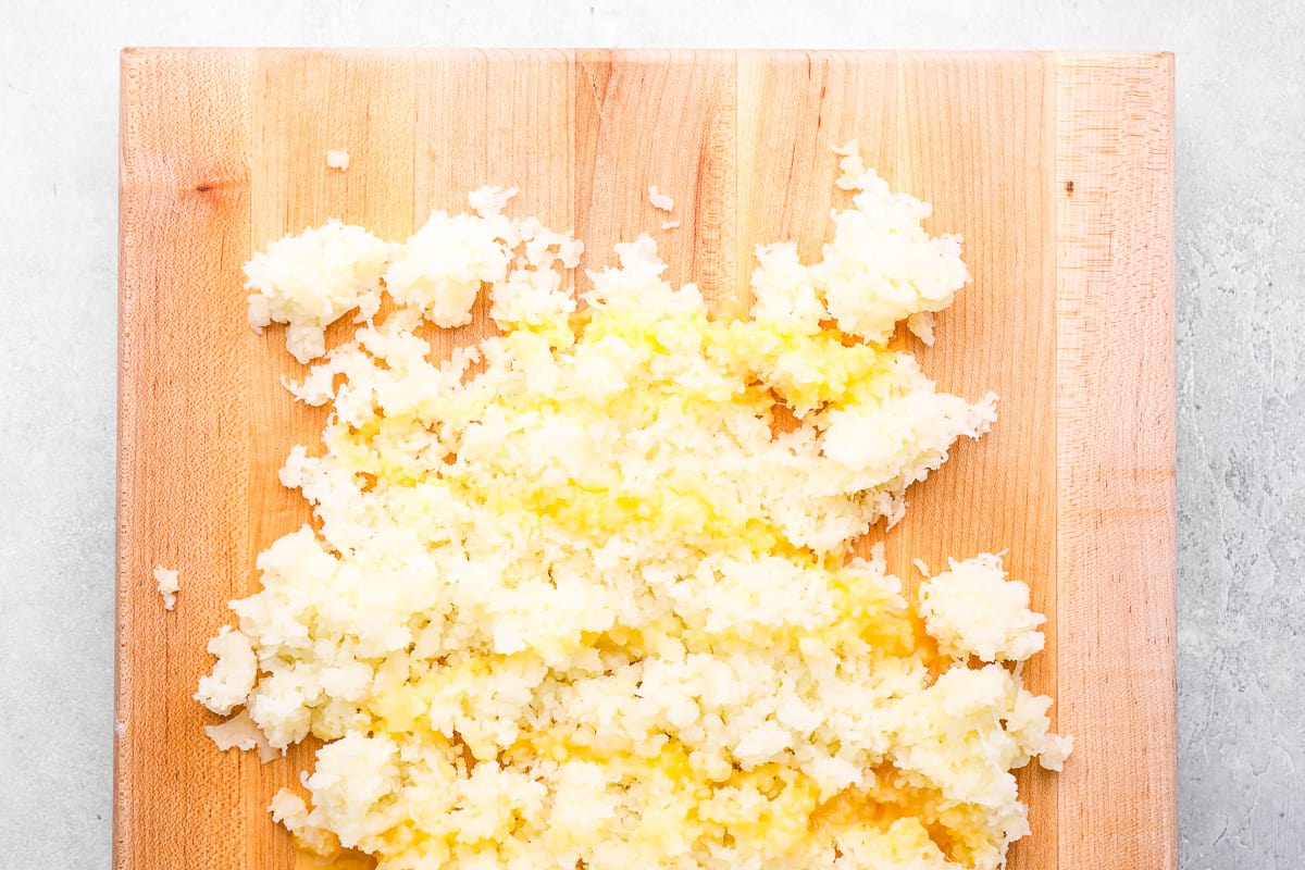 shredded potatoes with egg on a wooden cutting board.