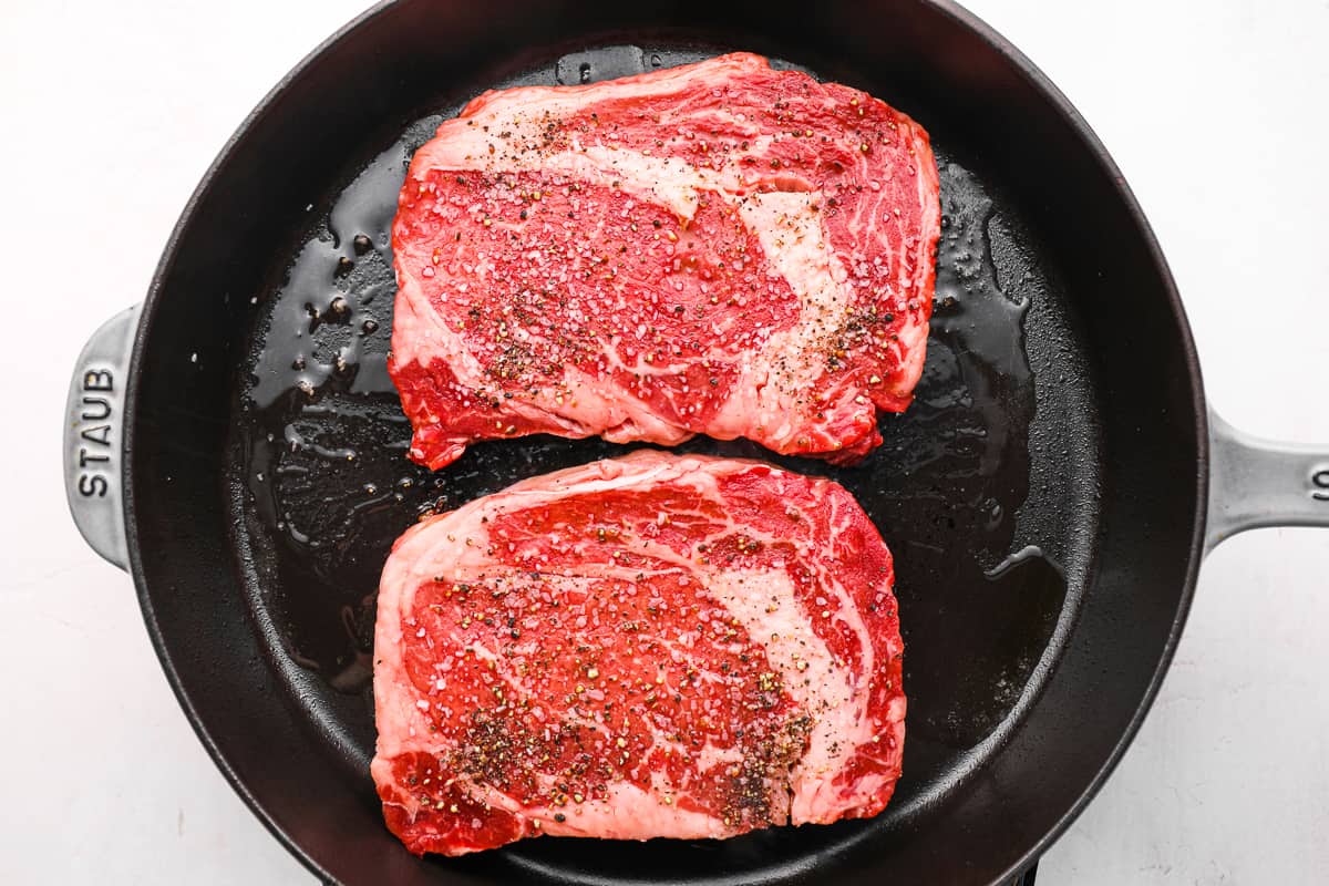 2 seasoned steaks in a cast iron skillet.