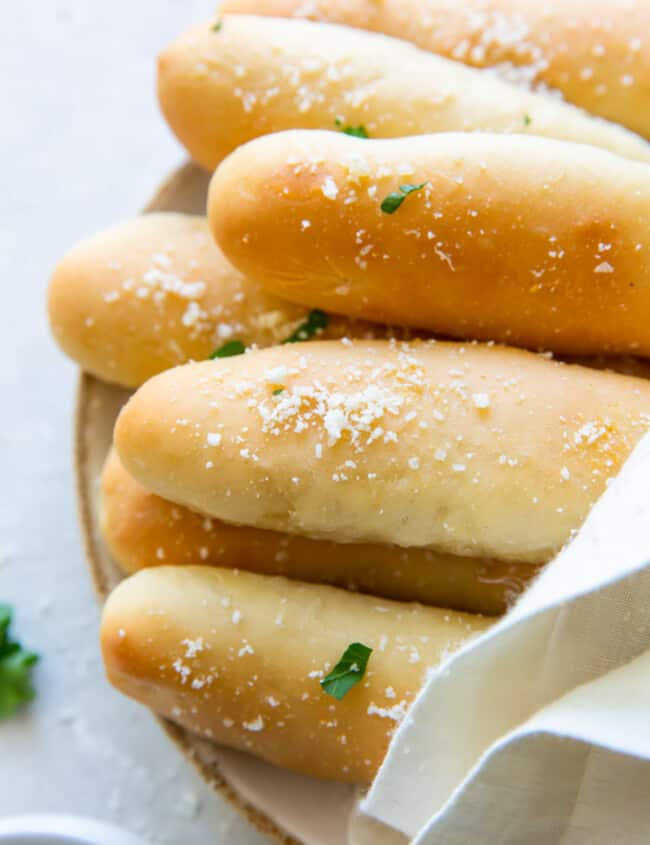 olive garden breadsticks on a white plate with a towel draped over them.