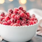 Sugared cranberries in a white bowl on a table.