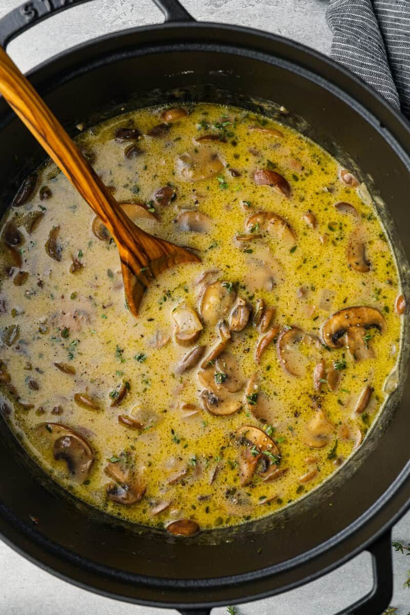 overhead view of mushroom soup in a dutch oven with a wooden spoon.