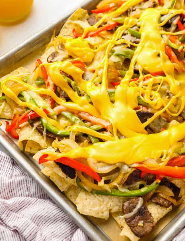 partial view of philly cheesesteak nachos on a baking sheet.