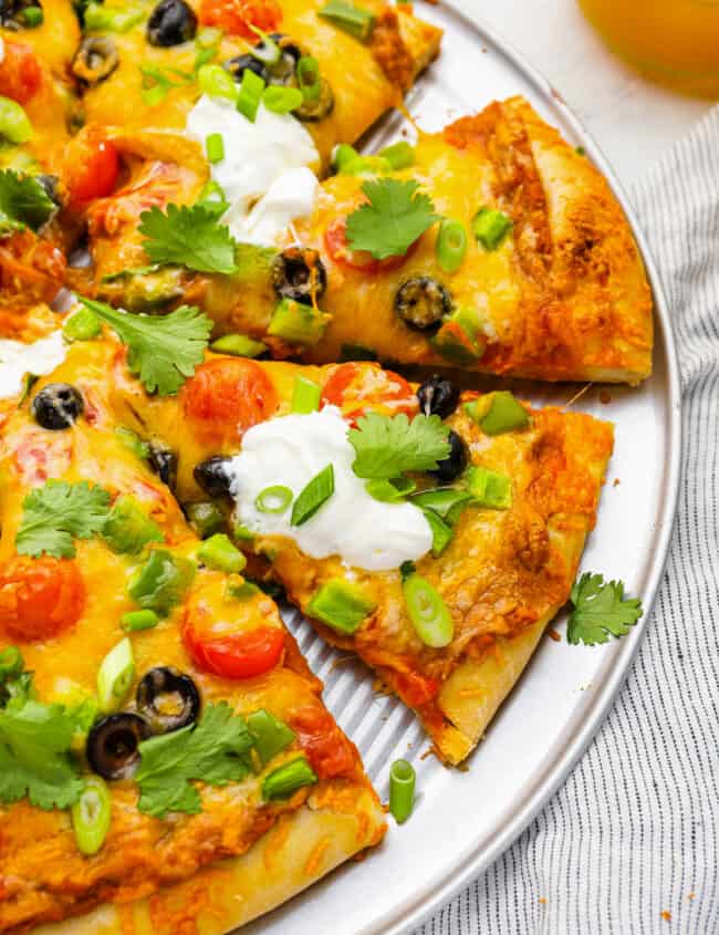 partial view of a sliced taco pizza on a pizza pan.