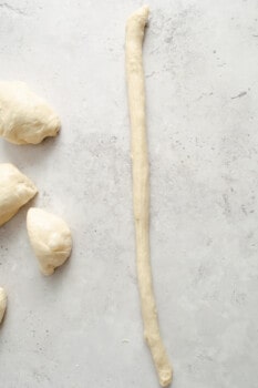 a piece of homemade pretzel dough rolled out into a long log.