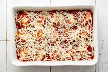 cheese sprinkled over zucchini ravioli in a rectangular baking pan.