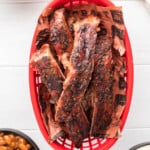 overhead view of smoked ribs in a red plastic basket.