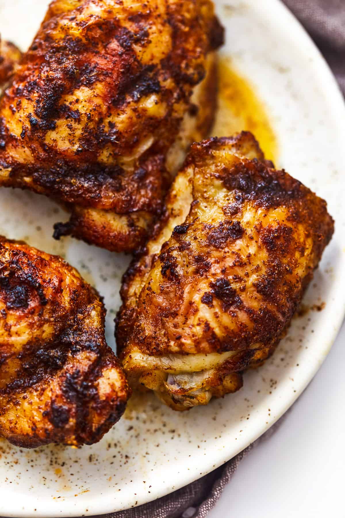 3 air fryer chicken thighs on a white plate.