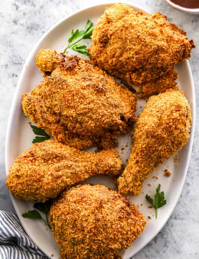 overhead view of 5 pieces of air fryer fried chicken on a white oval serving platter.