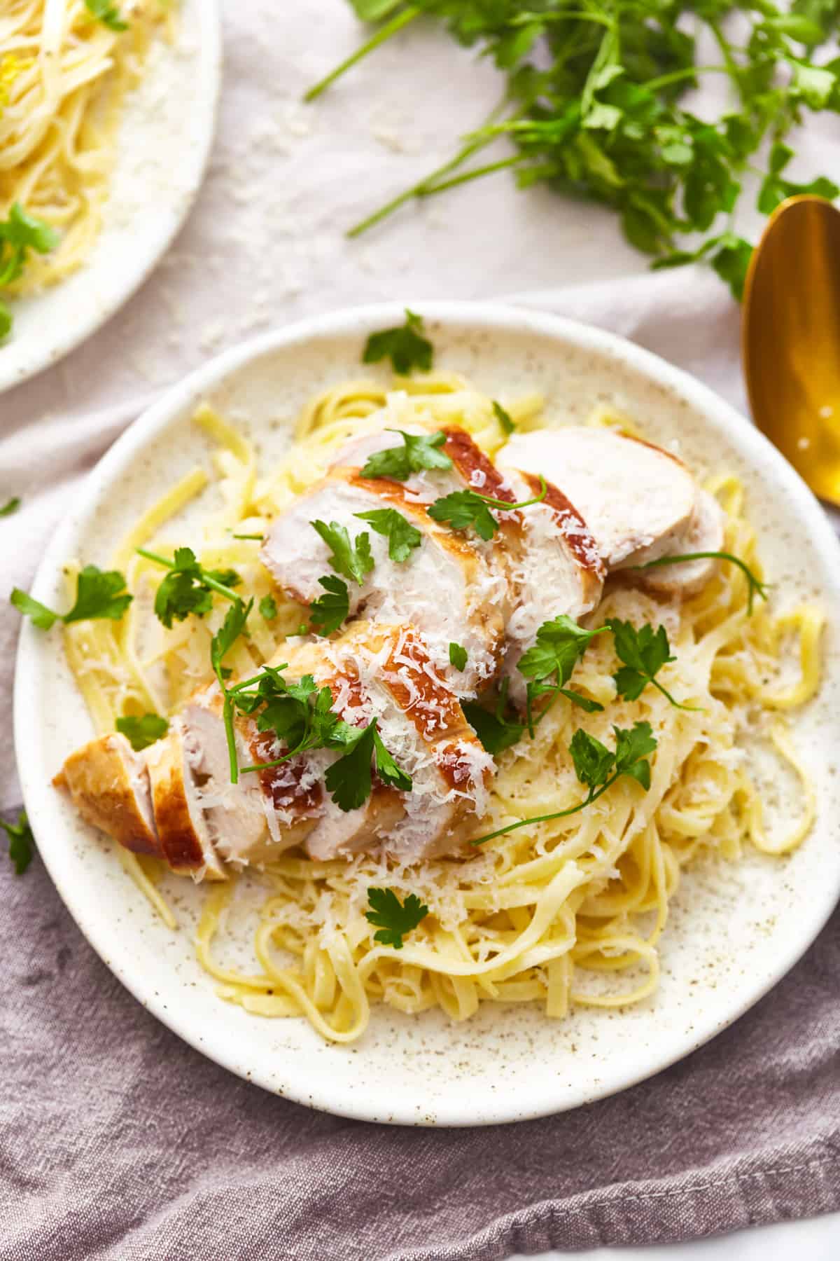 overhead view of a serving of chicken alfredo on a white plate.