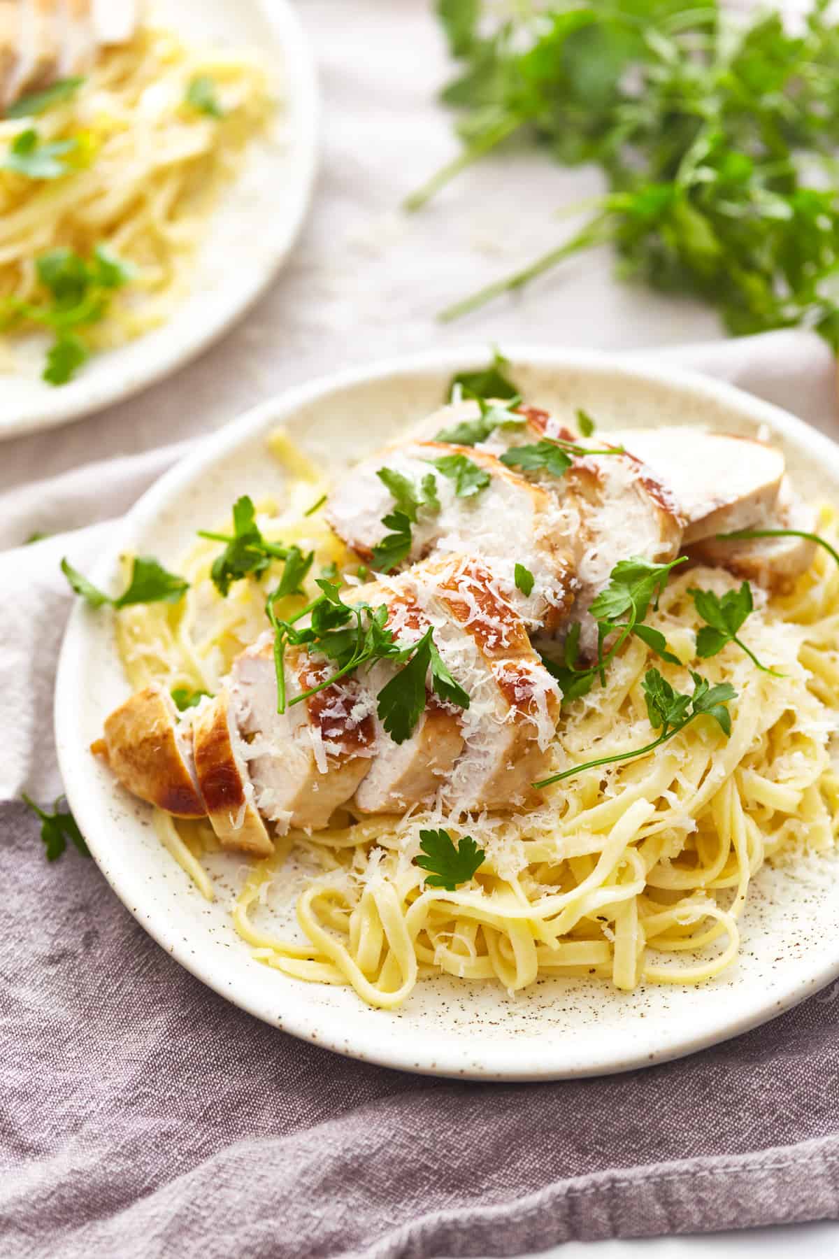 three-quarters view of a serving of chicken alfredo on a white plate.