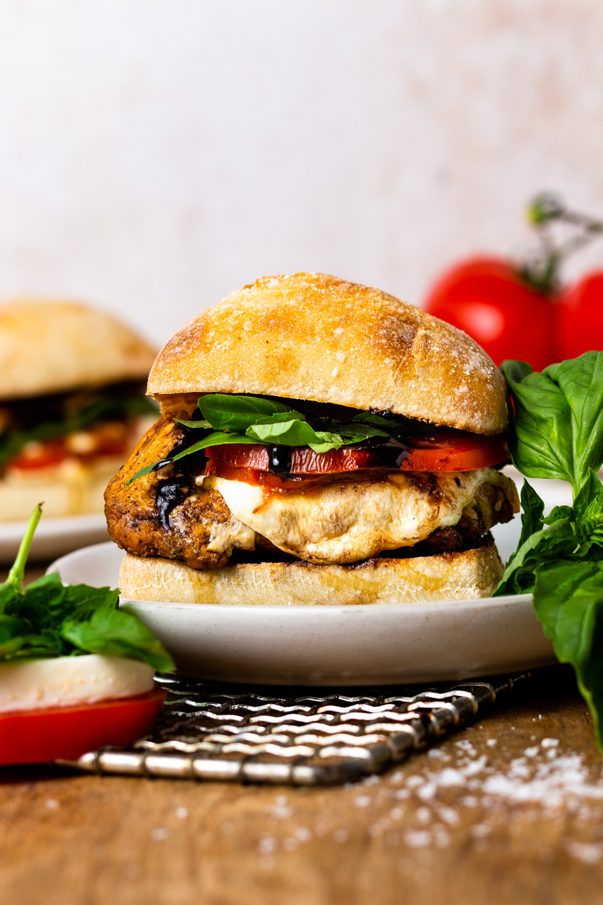 side view of a stuffed chicken caprese sandwich on a white plate.