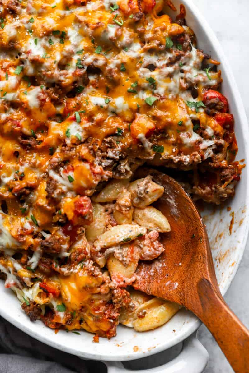 overhead view of hamburger casserole in a white oval casserole dish with a wooden spoon.