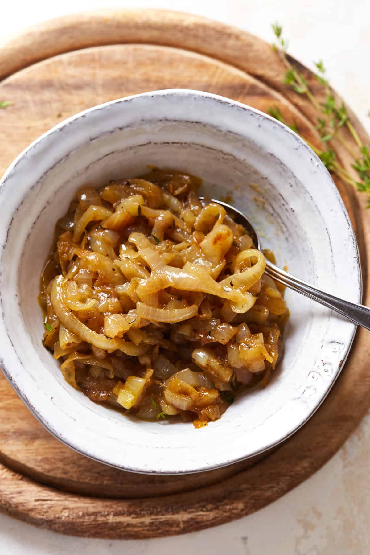 overhead view of caramelized onions in a white bowl with a spoon.