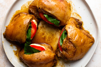 marinated caprese stuffed chicken breasts on a white plate.