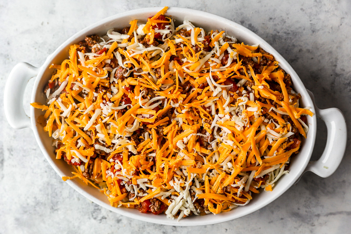 fully assembled unbaked hamburger casserole in a white casserole dish.