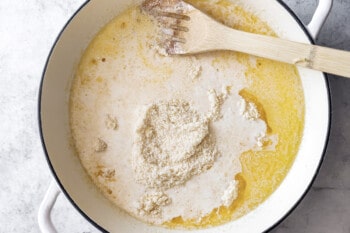 cheese added to butter and heavy cream in a white dutch oven.