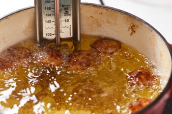 ranch fried pickles frying in a dutch oven with a thermometer.