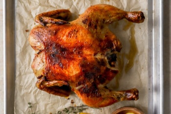 roasted spatchcock chicken on a parchment-lined baking sheet.