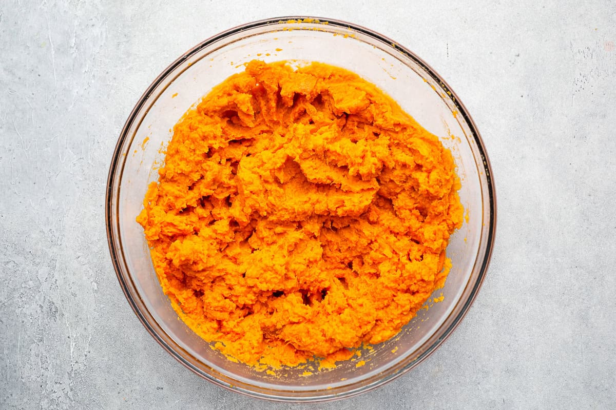 mashed sweet potatoes and butter in a glass bowl.