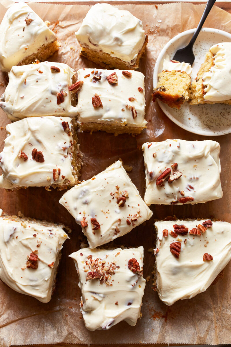 overhead view of a cut Italian cream cake with the slices askew and one slice in the top right corner on a small plate with a fork.