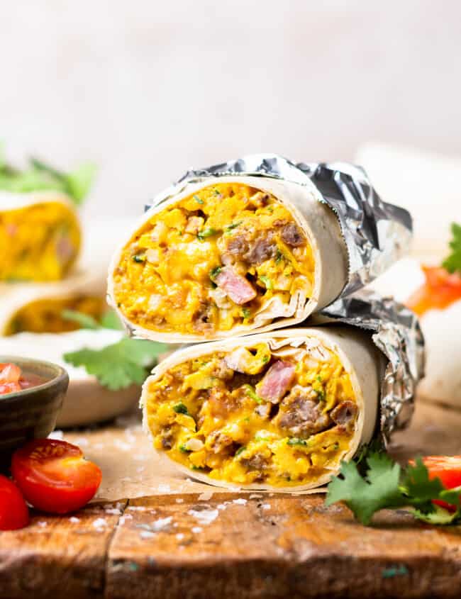 head-on view of a halved make ahead breakfast burrito wrapped in foil on a cutting board.