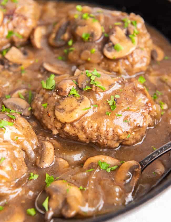 close up of salisbury steaks in a cast iron pan.