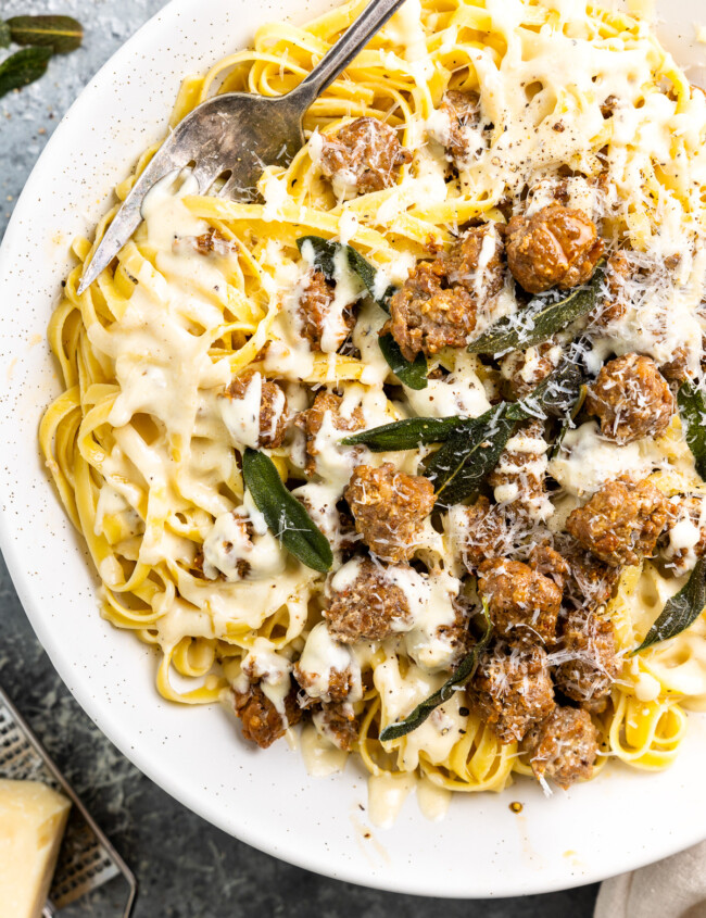 partial overhead view of fettuccini alfredo on a white plate.