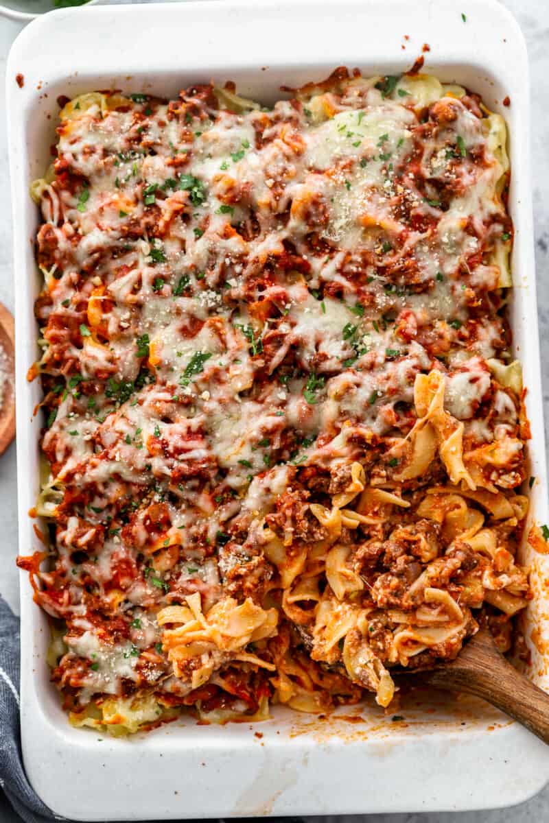 overhead view of sour cream noodle casserole with a wooden spoon in the lower right corner.